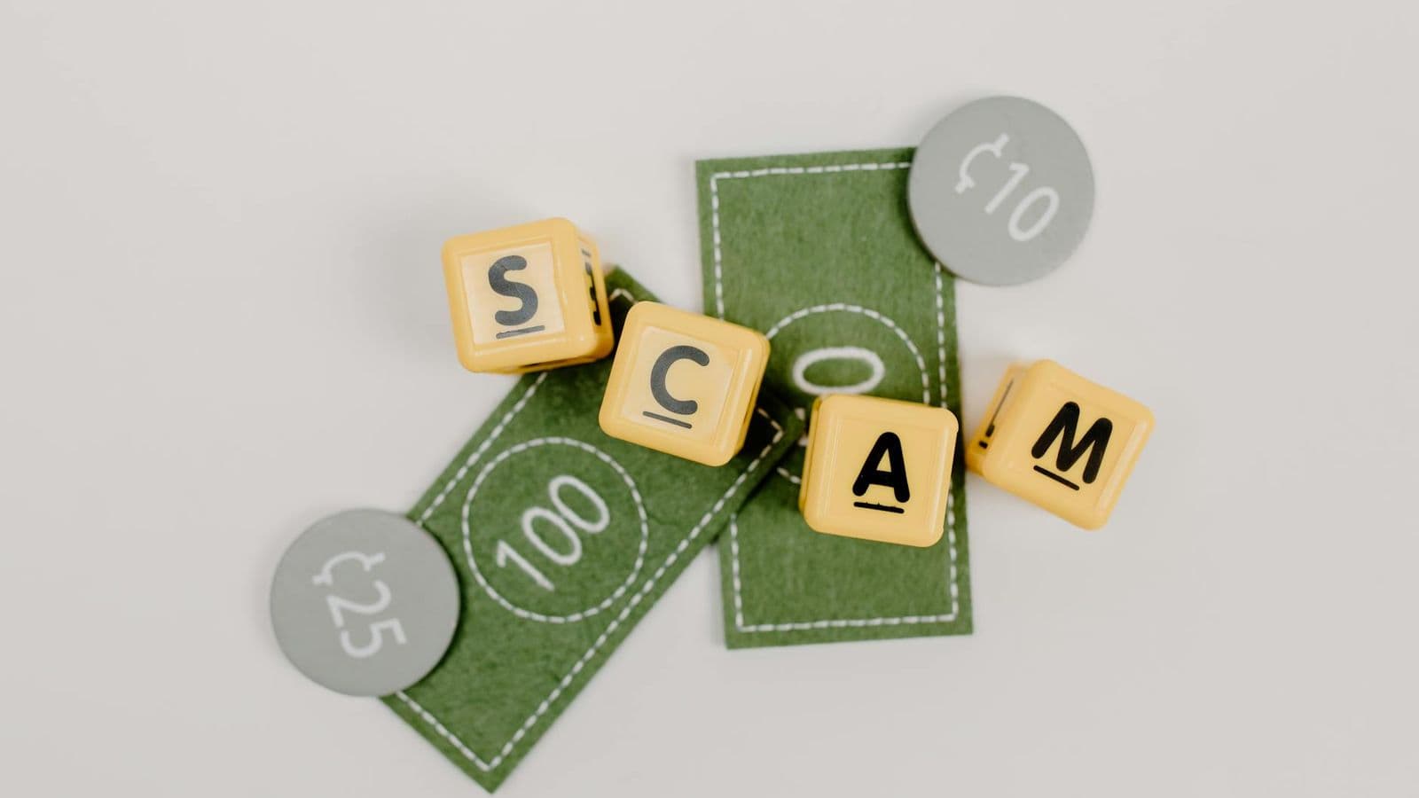 Yellow dice spelling 'Scam' on fake currency, representing financial deception.